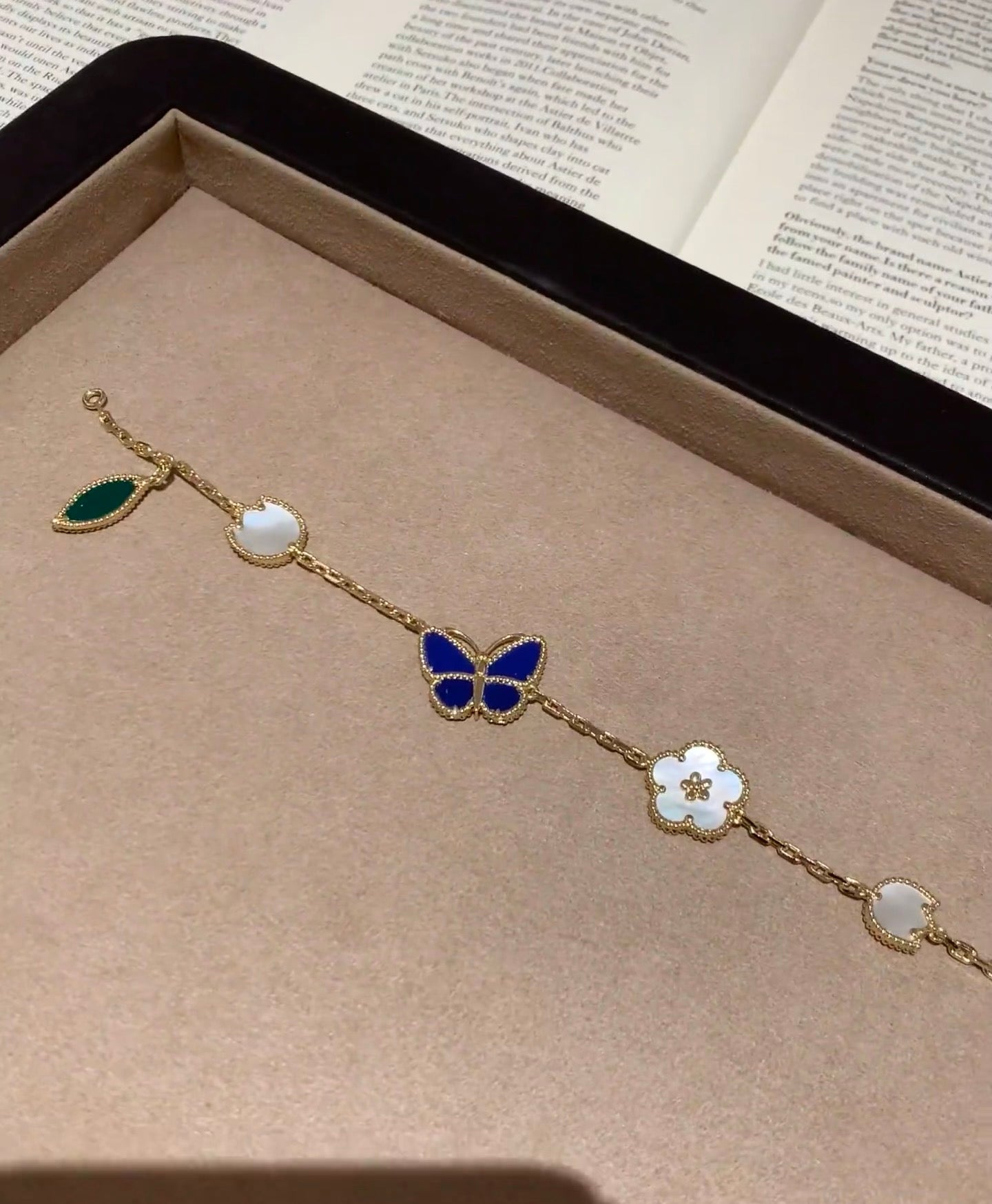 Gold-tone bracelet with blue butterfly, white clover, and green leaf charms