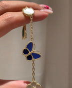 Gold-tone bracelet with blue butterfly charm and white clover flower charm