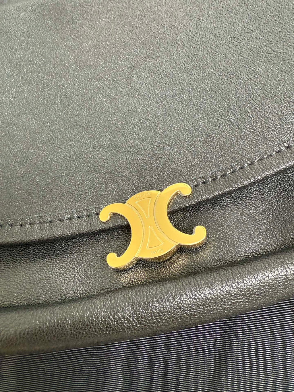 Gold logo on dark bag flap with stitched edge detail