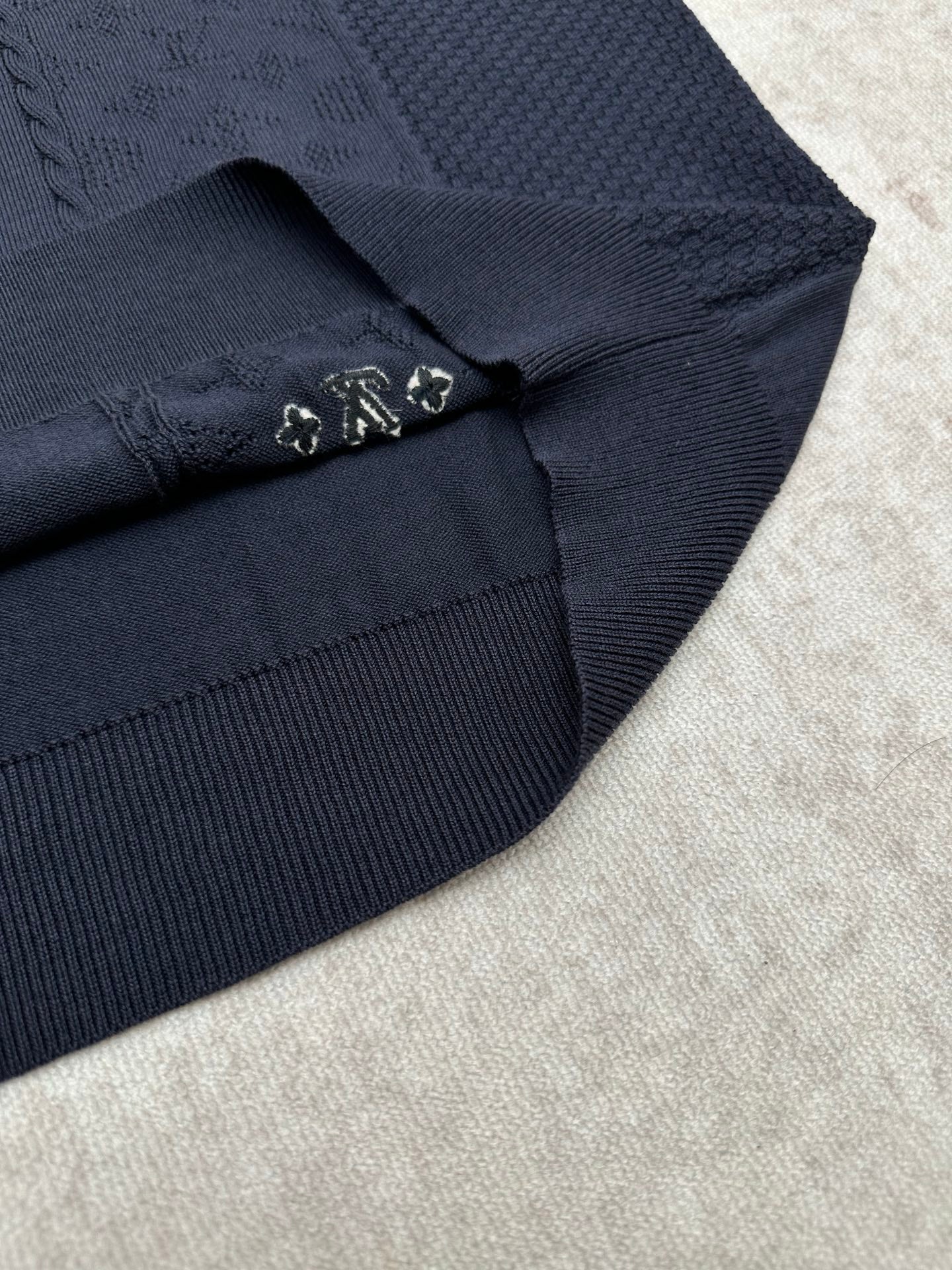 Navy polo shirt sleeve cuff detail with small metal embellishment