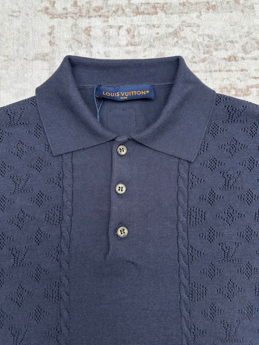 Navy polo shirt with open collar, three buttons, and neck brand label