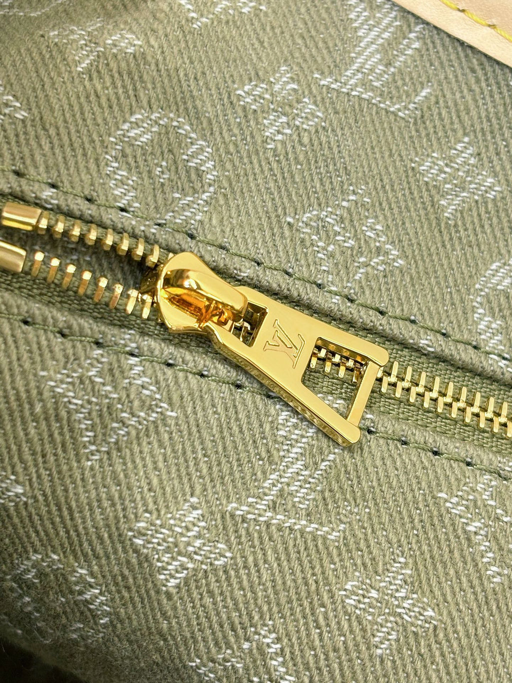 Louis Vuitton monogram zipper pull on olive-gray canvas, gold-tone hardware.