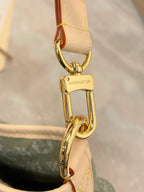 Louis Vuitton clasp and D-ring on tan leather strap over olive-gray monogram bag.