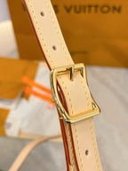 Louis Vuitton buckle on tan leather strap with gold hardware on olive-gray monogram bag.