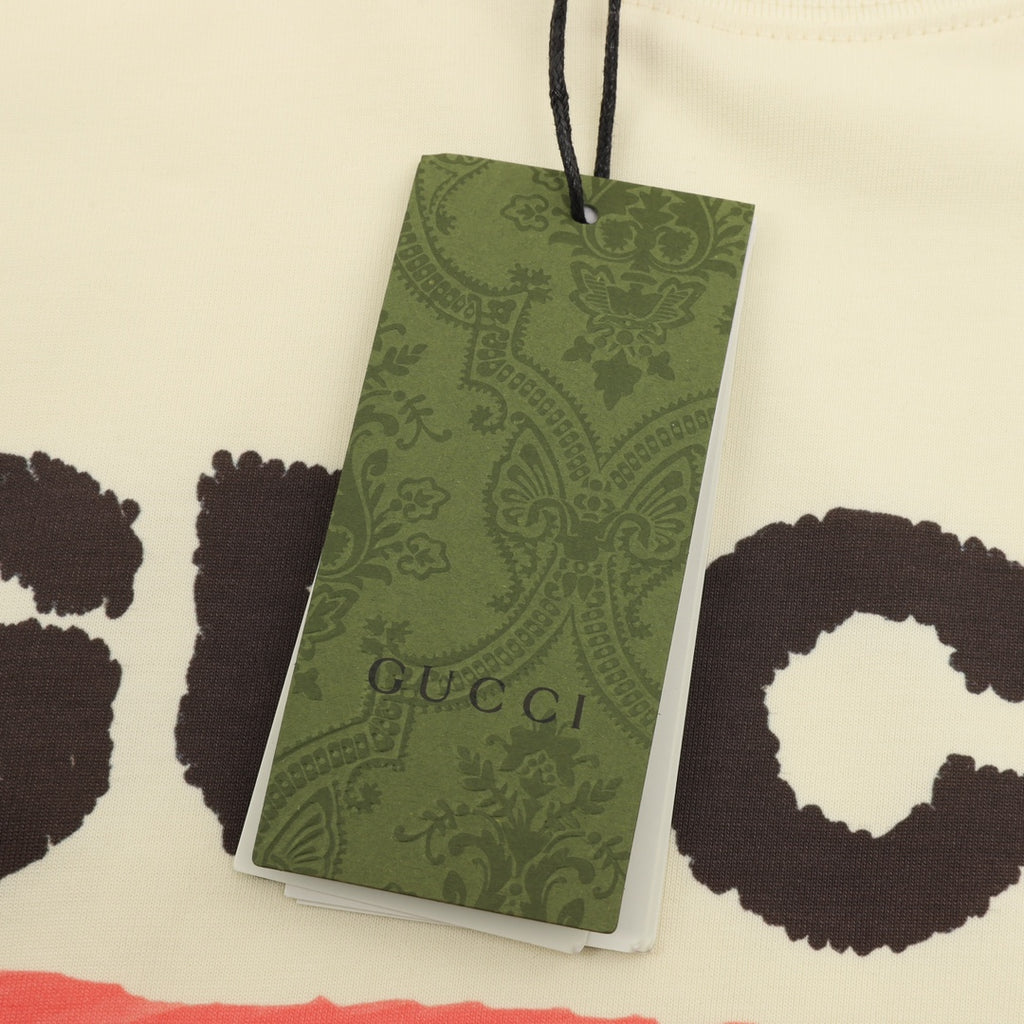 Cream T-shirt with green Gucci hang tag attached