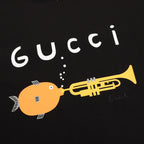 Black T-shirt close-up with white Gucci text and yellow trumpet character graphic