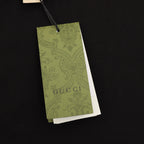 Black T-shirt with green Gucci hang tag attached by string