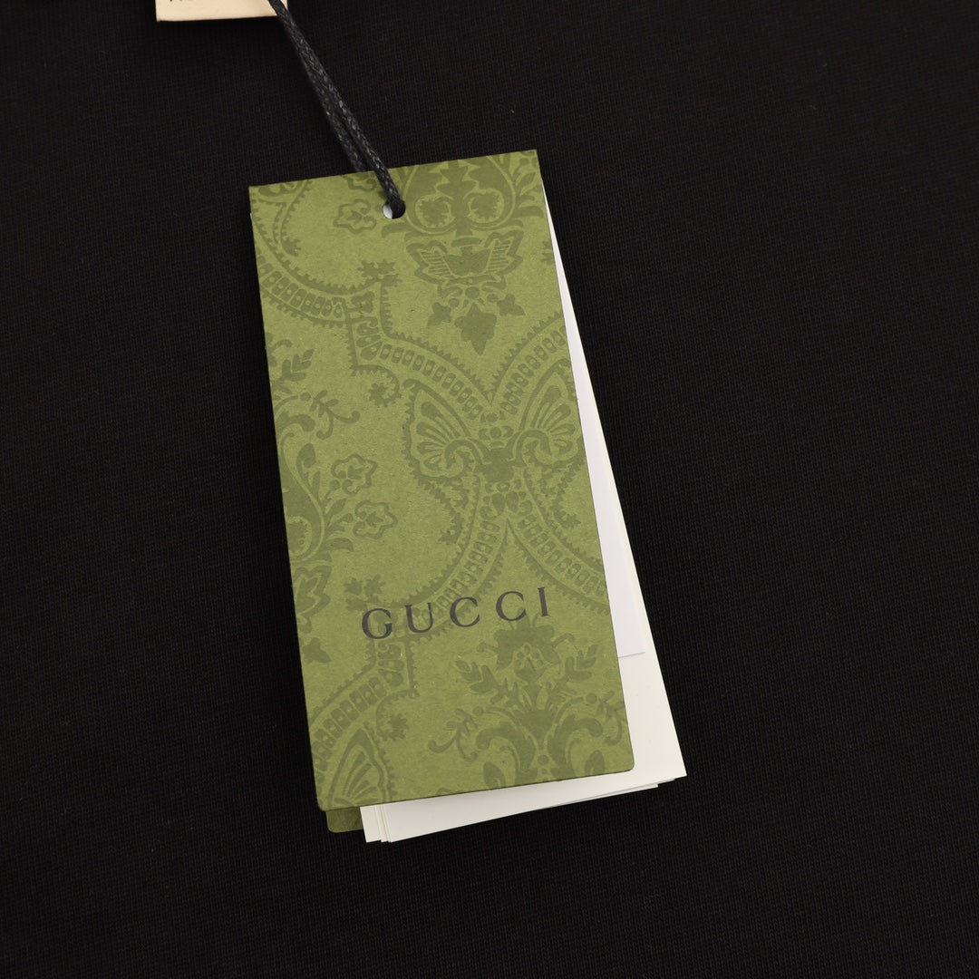 Black T-shirt with green Gucci hang tag attached by string