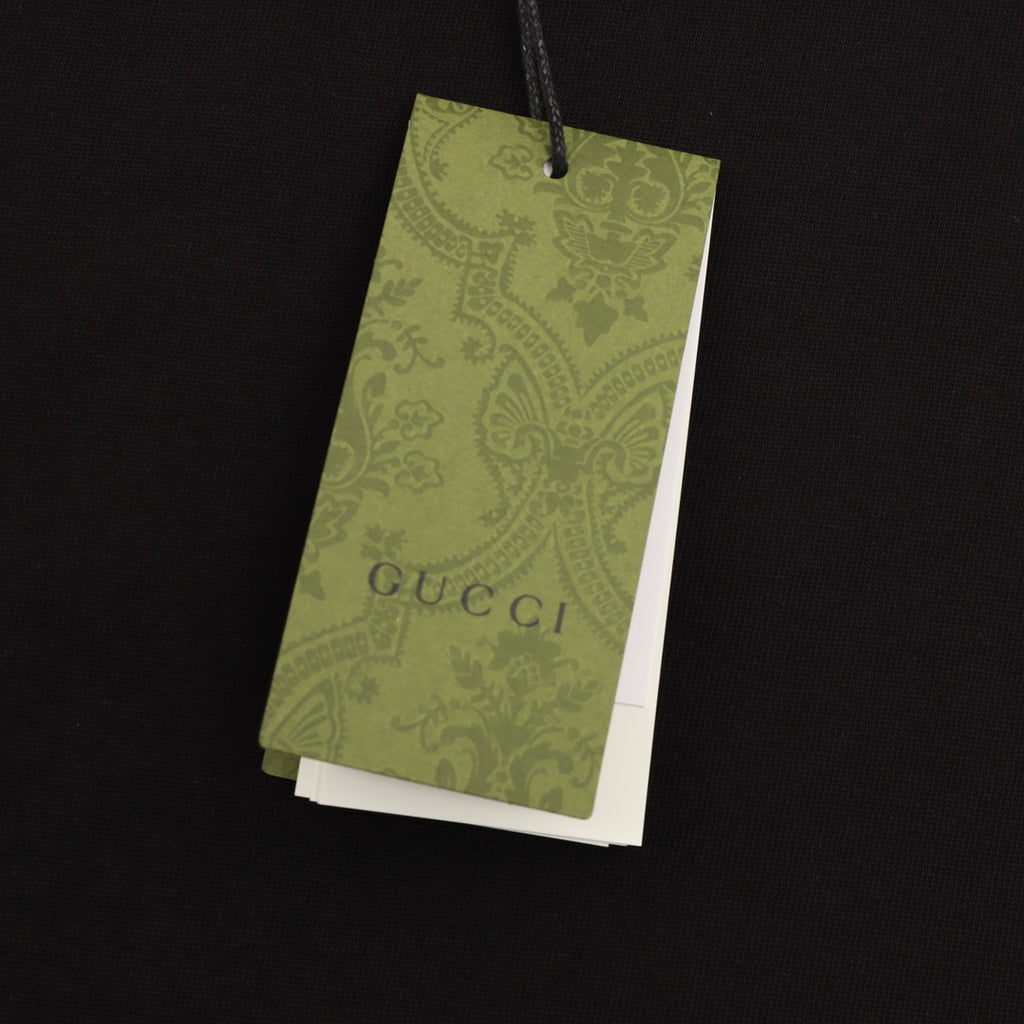 Black short-sleeve T-shirt with hanging green Gucci care tag