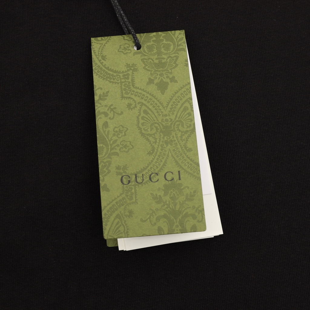 Black T-shirt with hanging green Gucci product tag