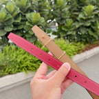 Red and tan leather belt straps with hole rows and gold buckle tabs