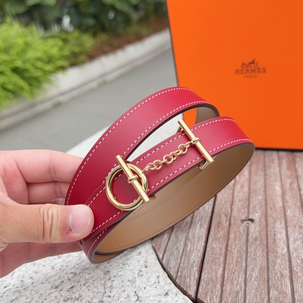 Red leather belt buckle close-up with gold hardware and chain link detail