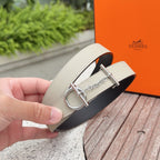 Hermes belt with light beige strap and black underside, held in hand