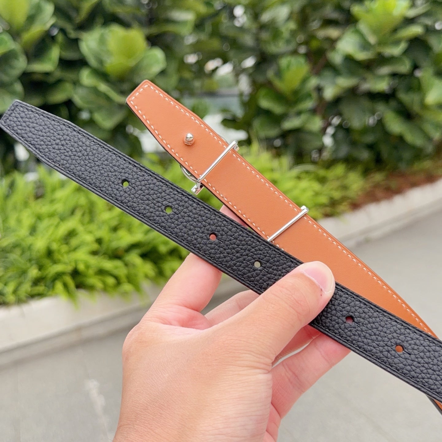 Hermes belt in dark leather with tan underside and punched adjustment holes