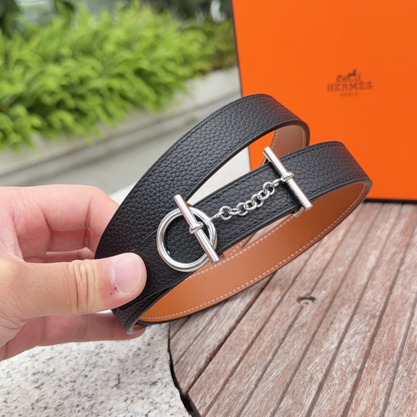 Hermes belt close-up: dark leather strap with silver ring buckle and chain