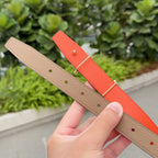 Hermes belt with tan and orange straps, gold buckle, and punched adjustment holes