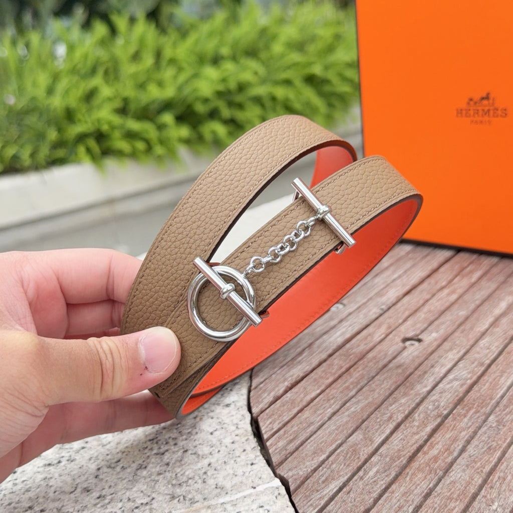 Tan leather belt close-up with silver double ring buckle and chain; orange lining