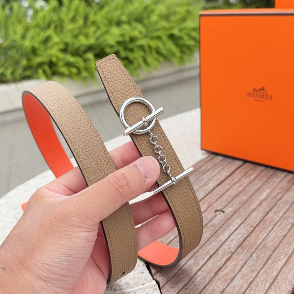 Tan leather belt with silver buckle hardware and orange inner lining; hand-held