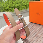 Tan leather belt with silver buckle hardware and orange inner lining; hand-held