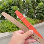 Two-tone leather belt: tan and bright orange straps with silver buckle and punched holes