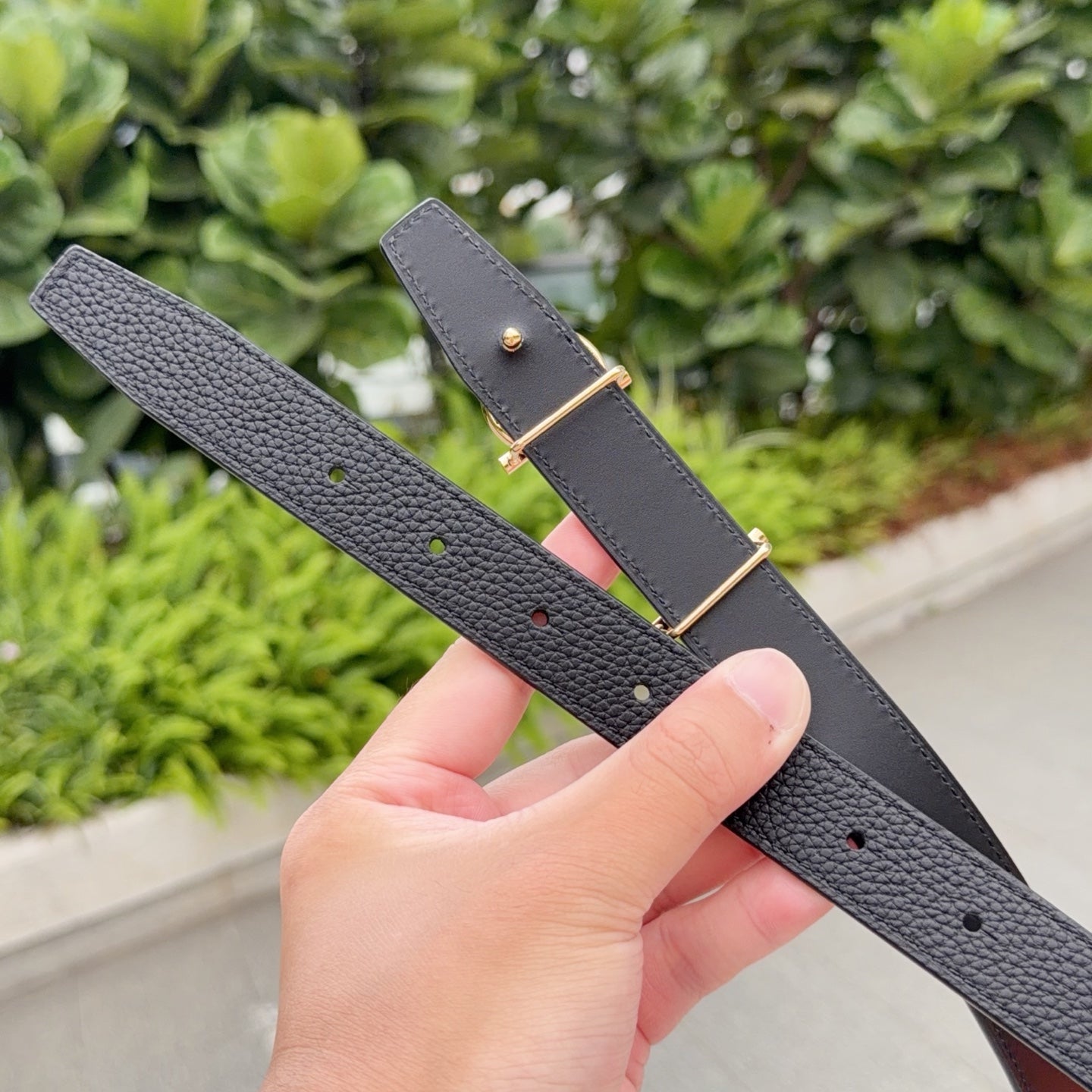 Gray leather belt with gold buckle and punched holes row