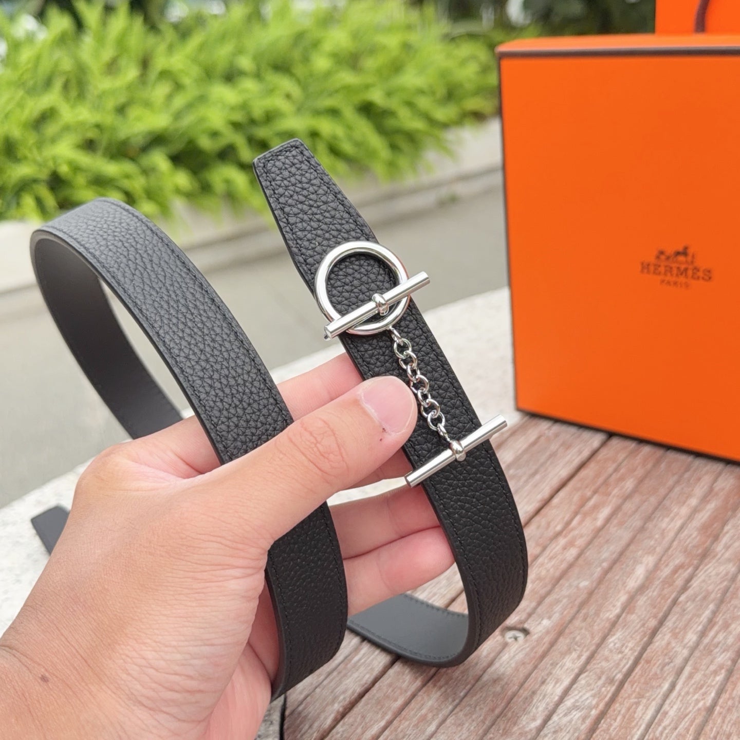 Hermes belt close-up with dark leather strap, D-ring buckle, and chain-link