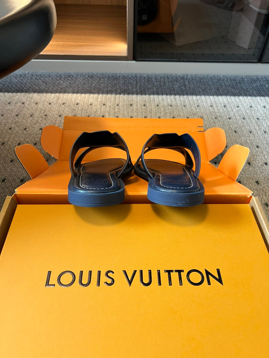 Louis Vuitton slide sandals, black with light blue straps, pair on display