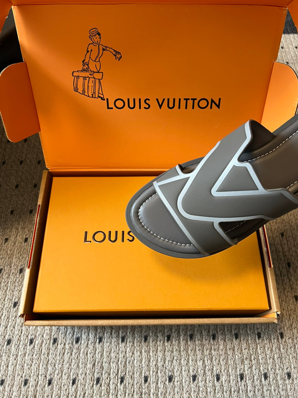 Louis Vuitton slide sandal close-up, dark gray upper with white V-shaped trim