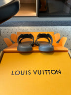 Louis Vuitton slide sandals on orange packaging, dark gray with white V-style straps