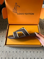 Dark slide sandals with white V strap, held over open shoe box