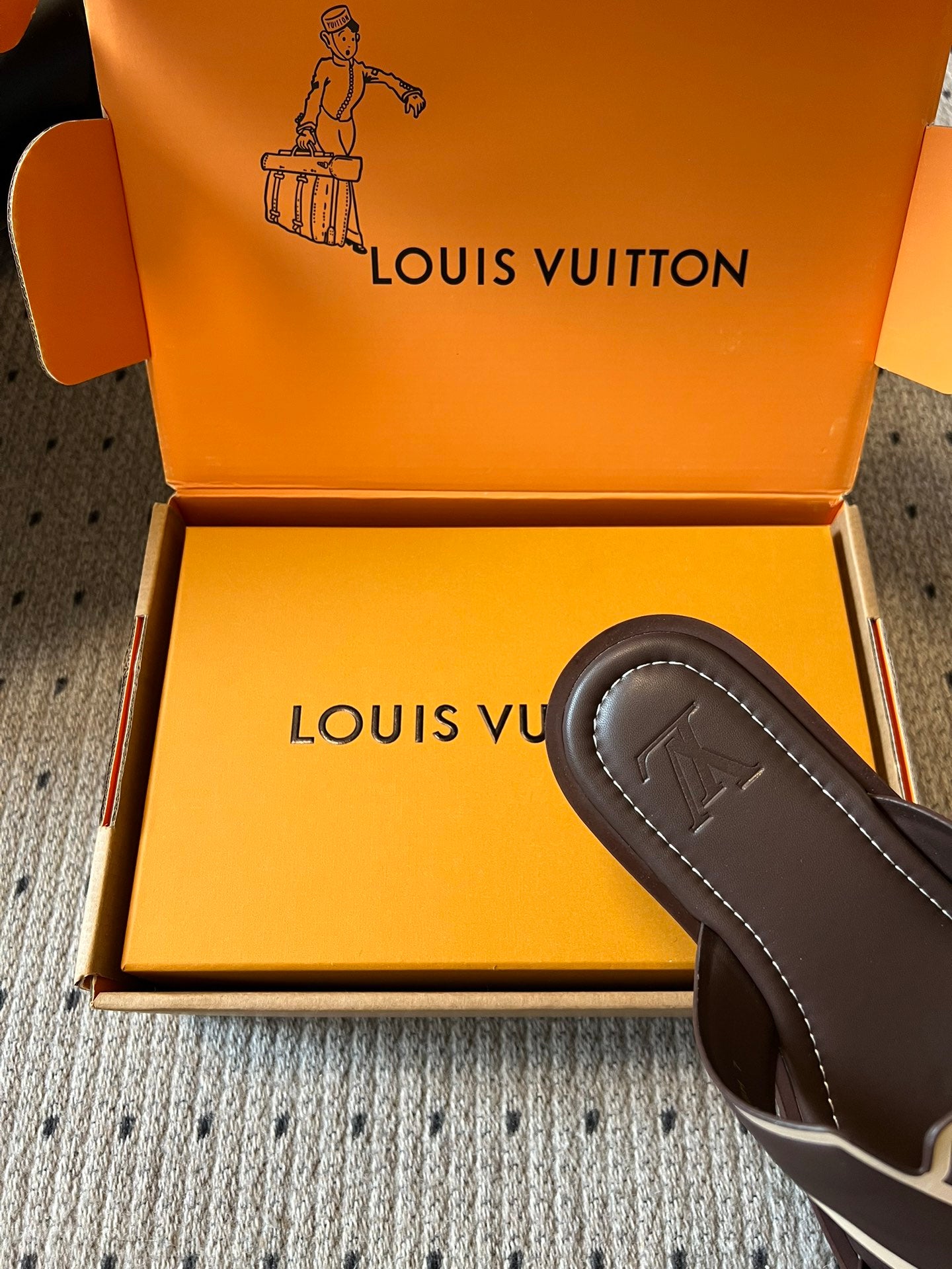 Dark slide sandal with embossed V logo on strap, in shoe box