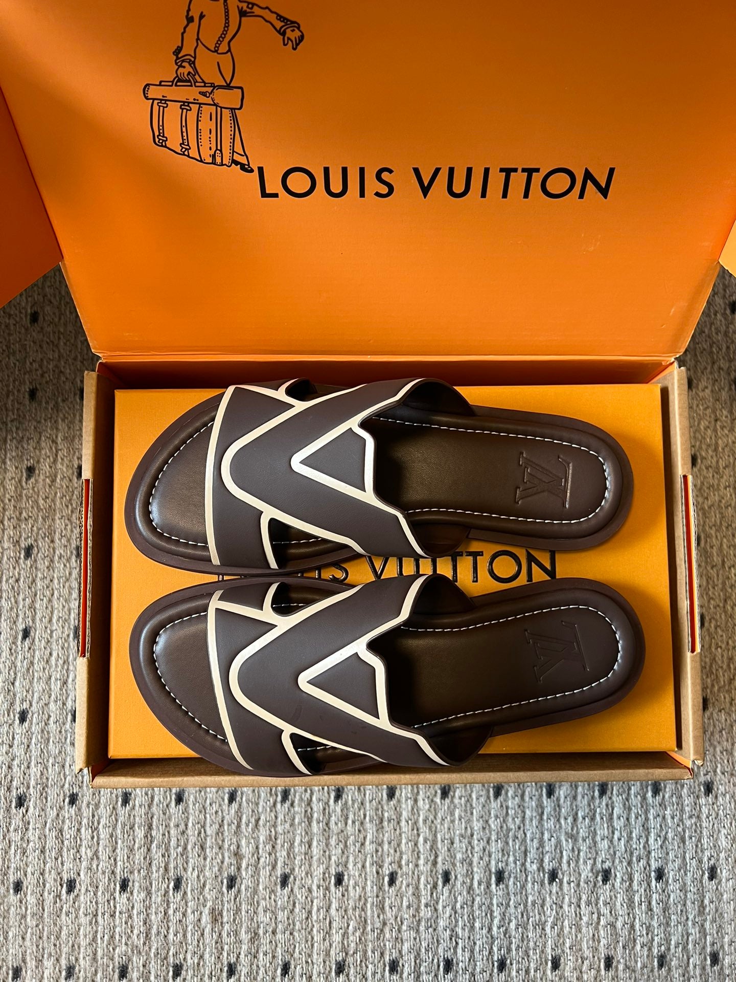 Two dark sandals with white V crossover straps in open box
