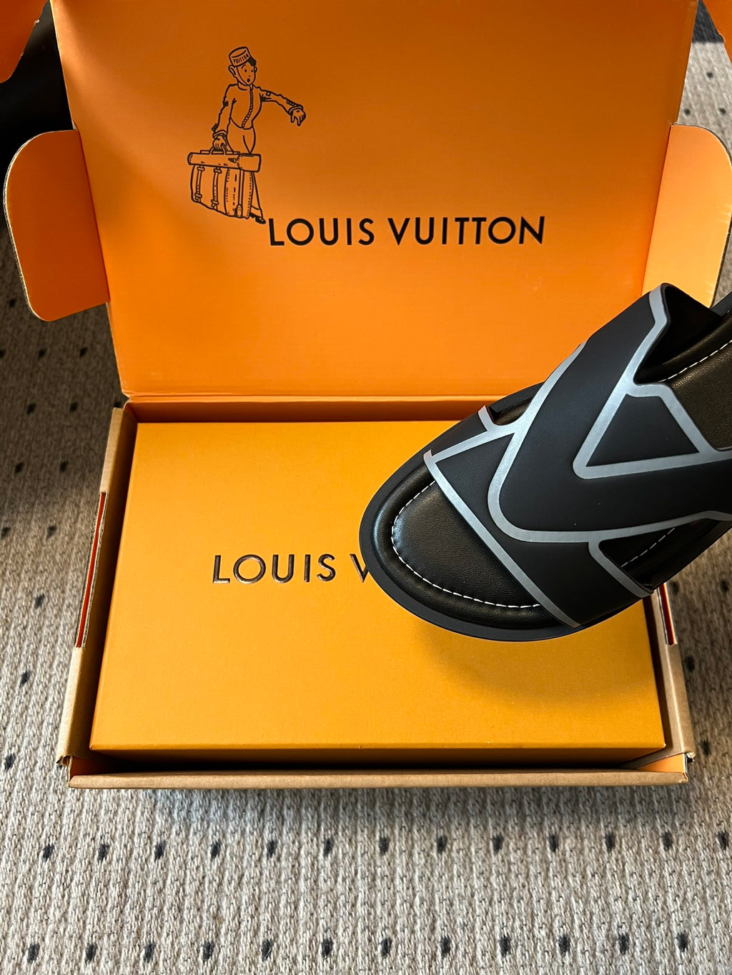 Louis Vuitton slide sandals, close-up of black strap with light blue V logo and black sole trim