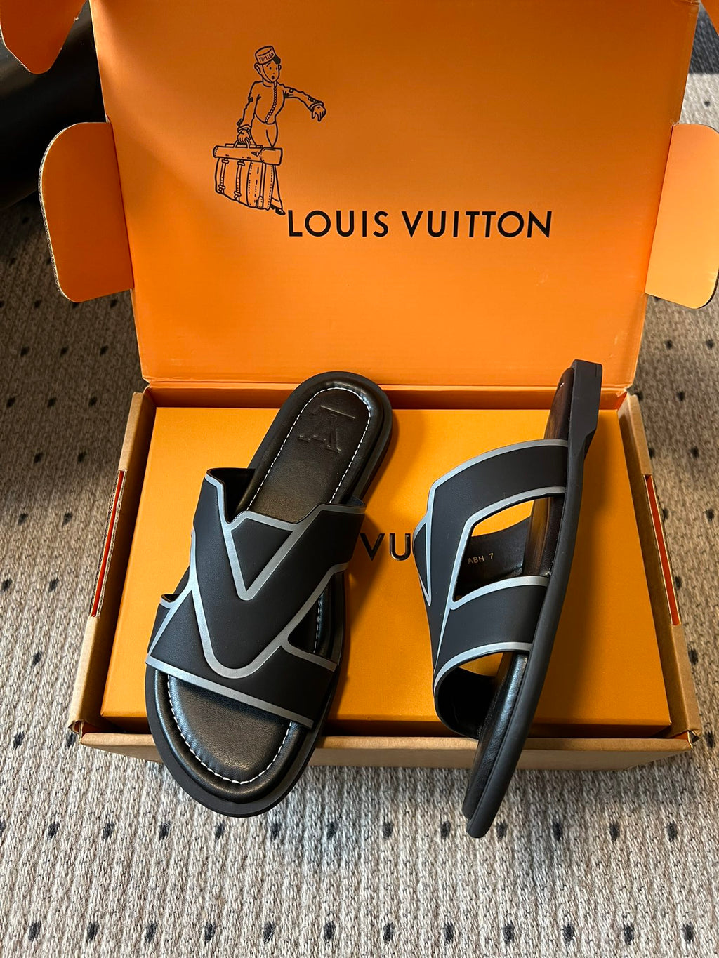 Louis Vuitton sandals with black slide strap and light blue V logo, shown in product box