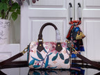 Floral print handbag front view with dark brown leather handles and gold hardware
