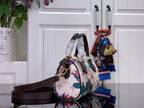 Floral print handbag side view with dark brown shoulder strap and top handles