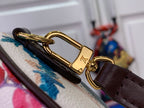 Gold-tone clasp on dark brown leather strap attached to floral handbag