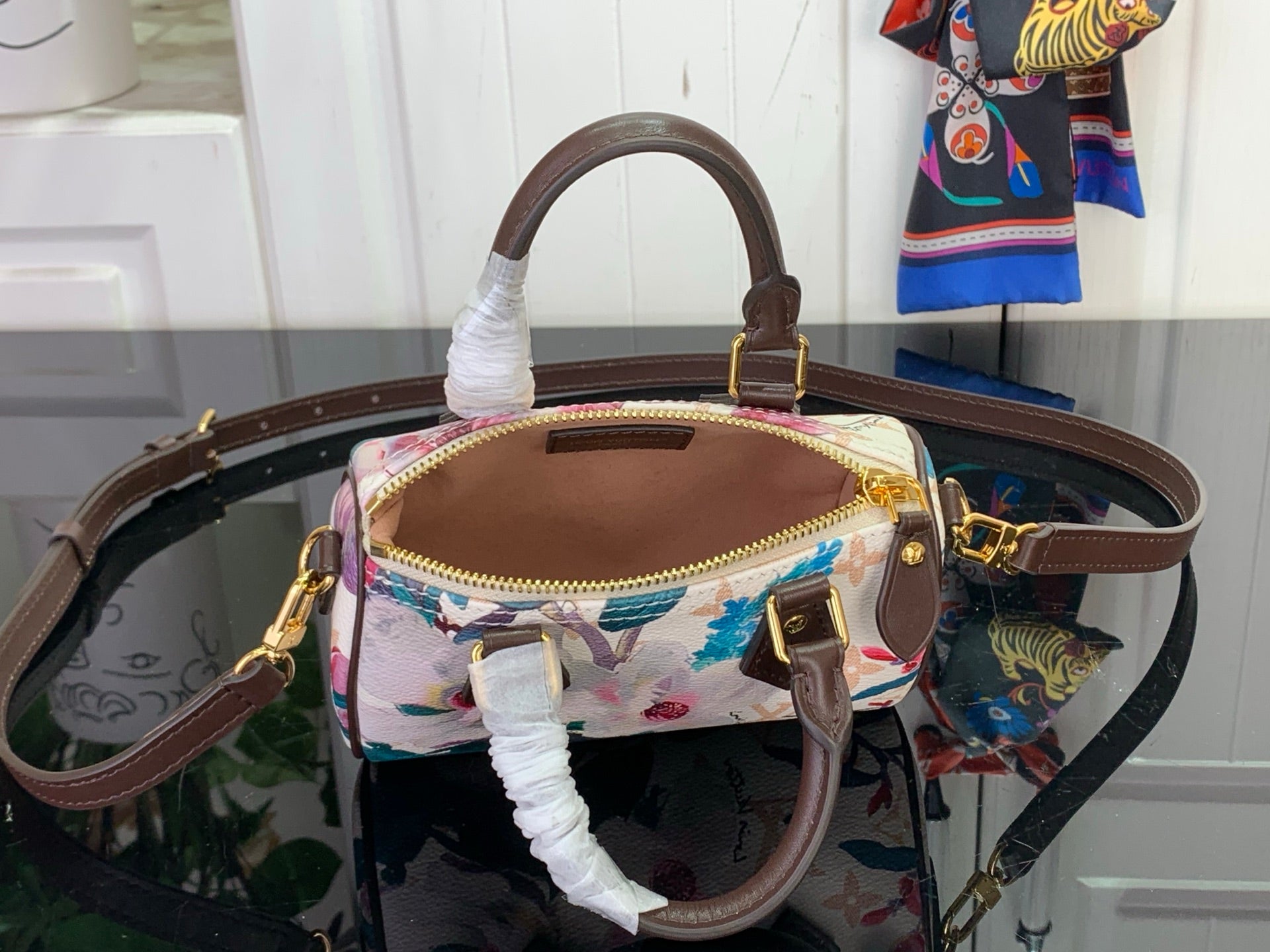 Floral print mini handbag with brown top handle, crossbody strap, and gold hardware