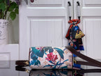 Floral print handbag with dark brown shoulder strap and decorative scarf