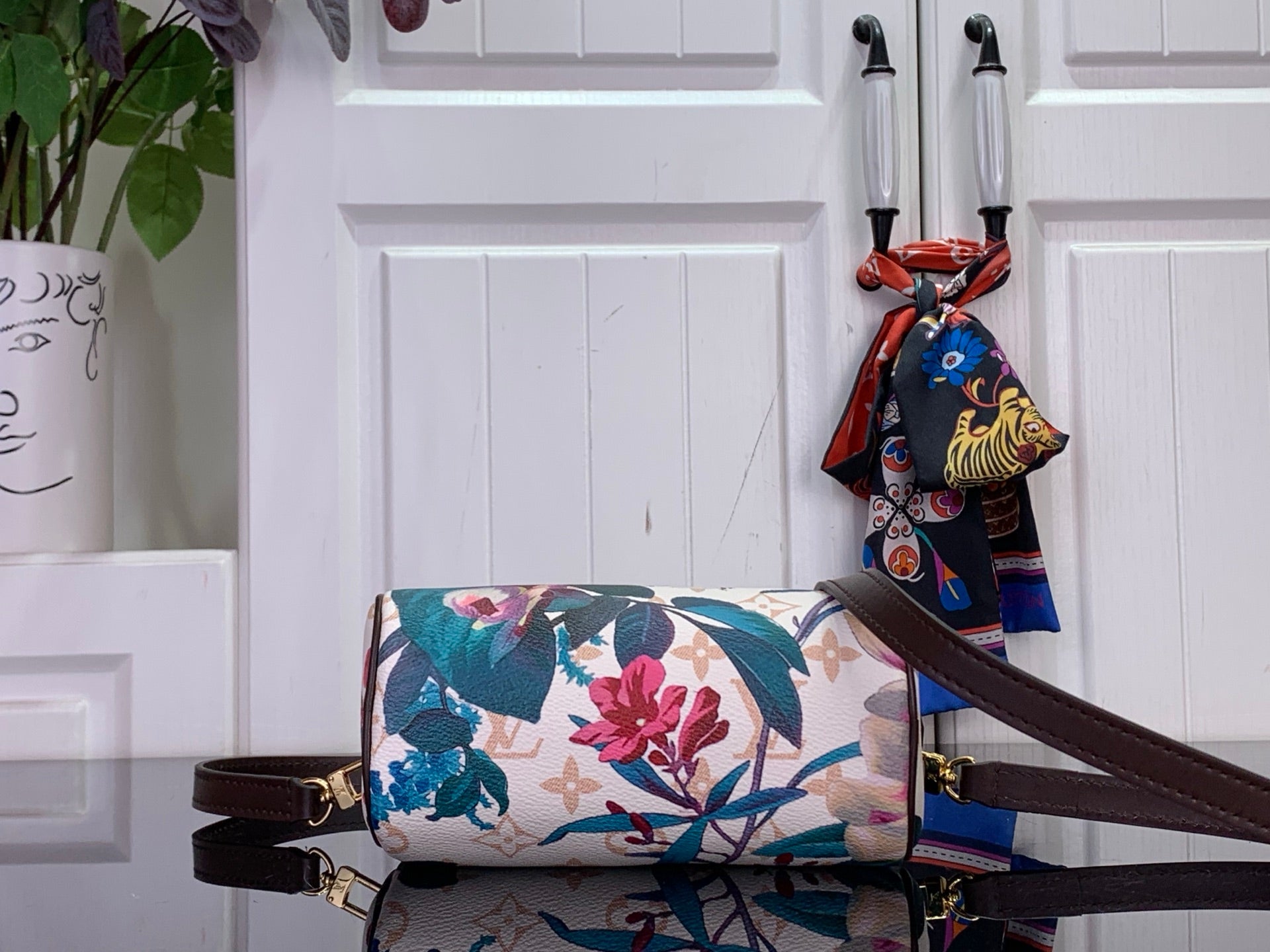 Floral print handbag with dark brown shoulder strap and decorative scarf