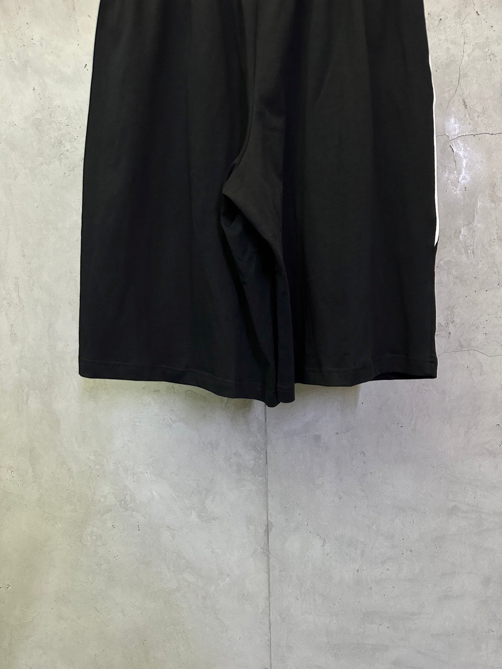 Black shorts back view with draped center fold and gathered waistband.
