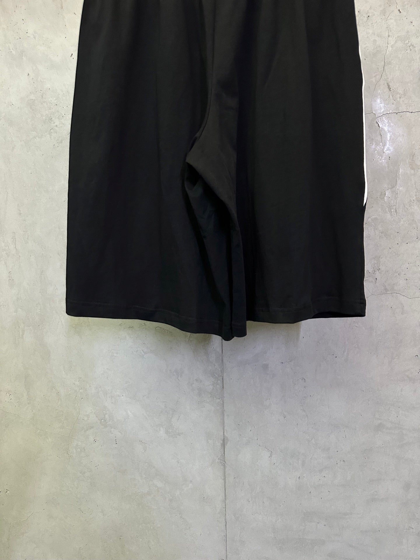 Black shorts back view with draped center fold and gathered waistband.