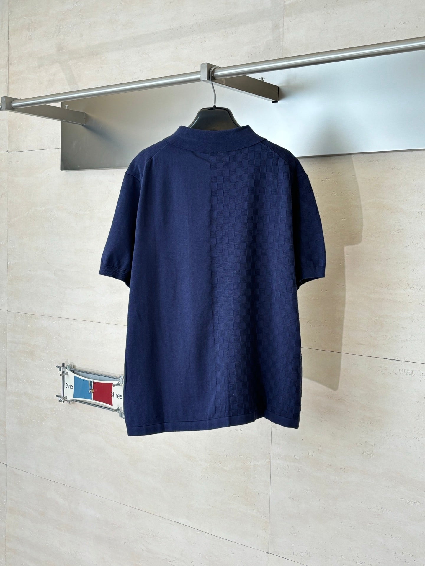 Navy short-sleeve polo shirt with collar and button front, back view