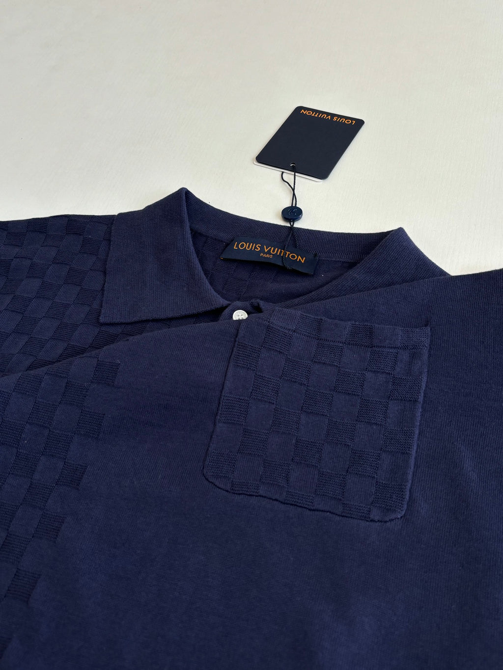 Navy polo shirt close-up with button placket, collar, and chest pocket