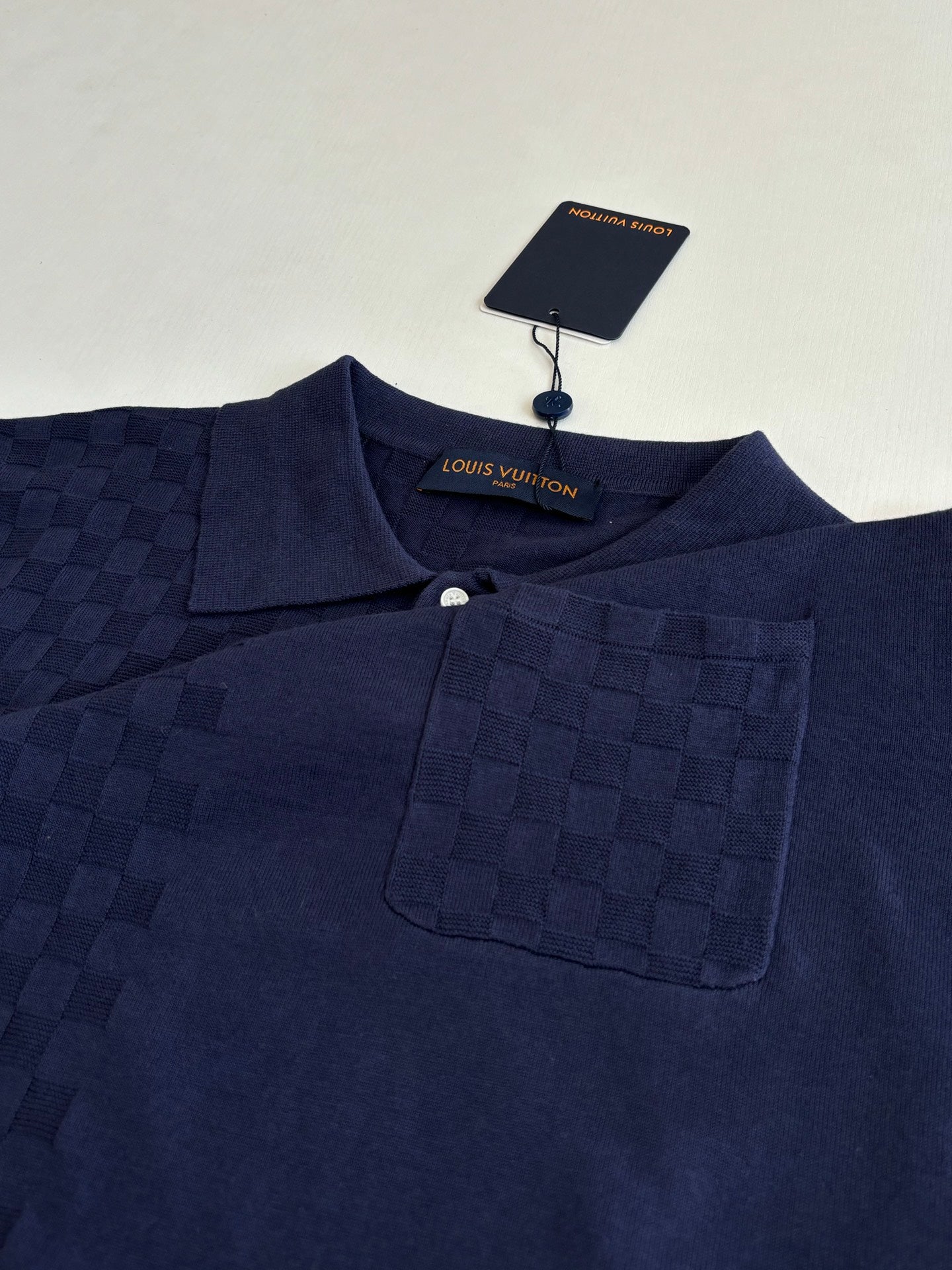 Navy polo shirt close-up with button placket, collar, and chest pocket