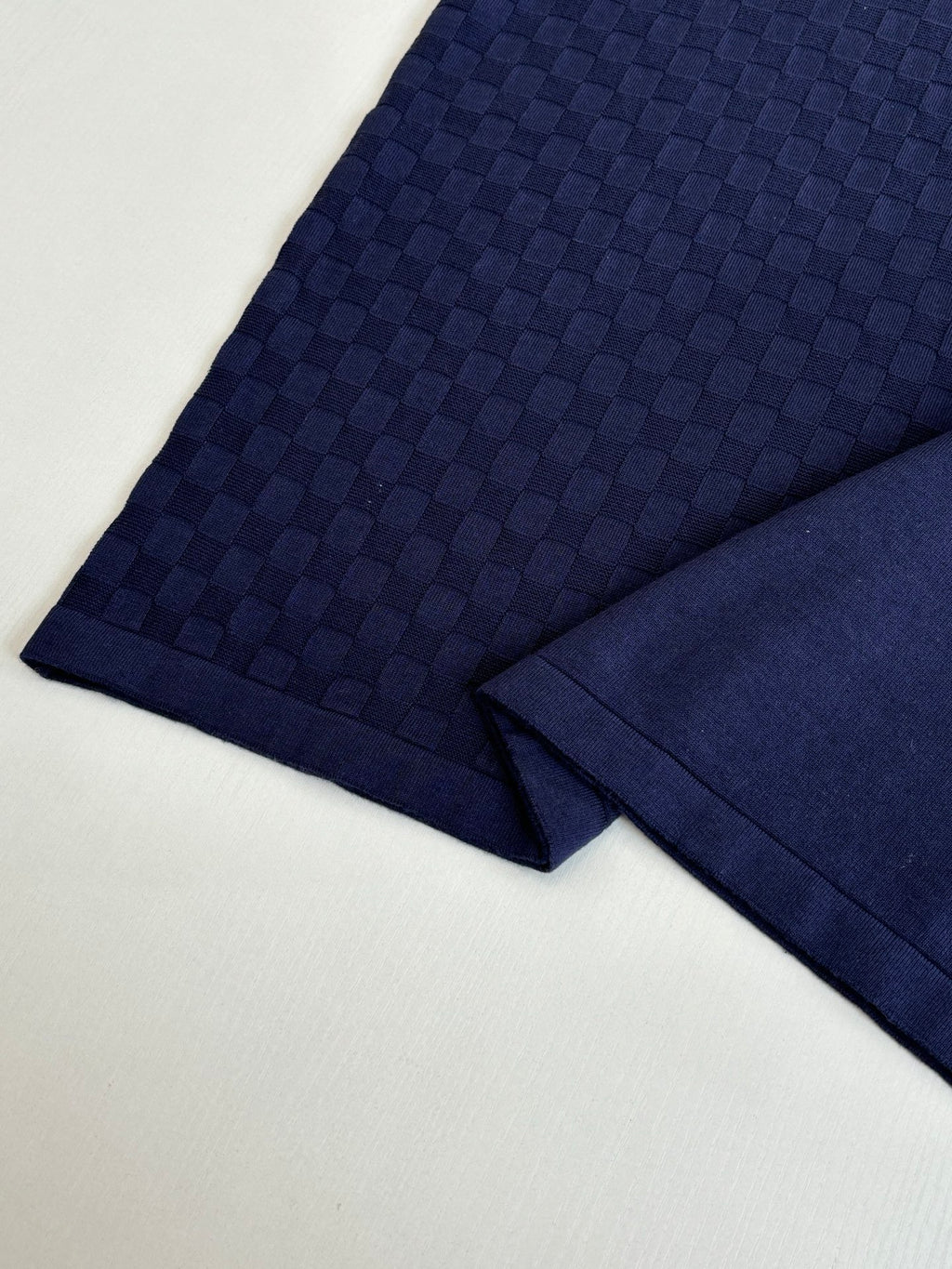 Navy polo shirt sleeve fabric close-up with textured check pattern