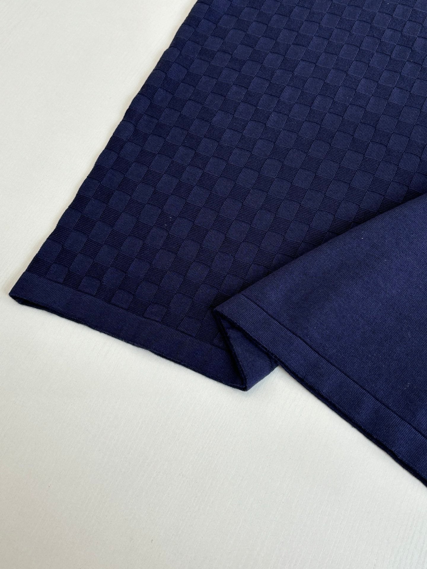 Navy polo shirt sleeve fabric close-up with textured check pattern