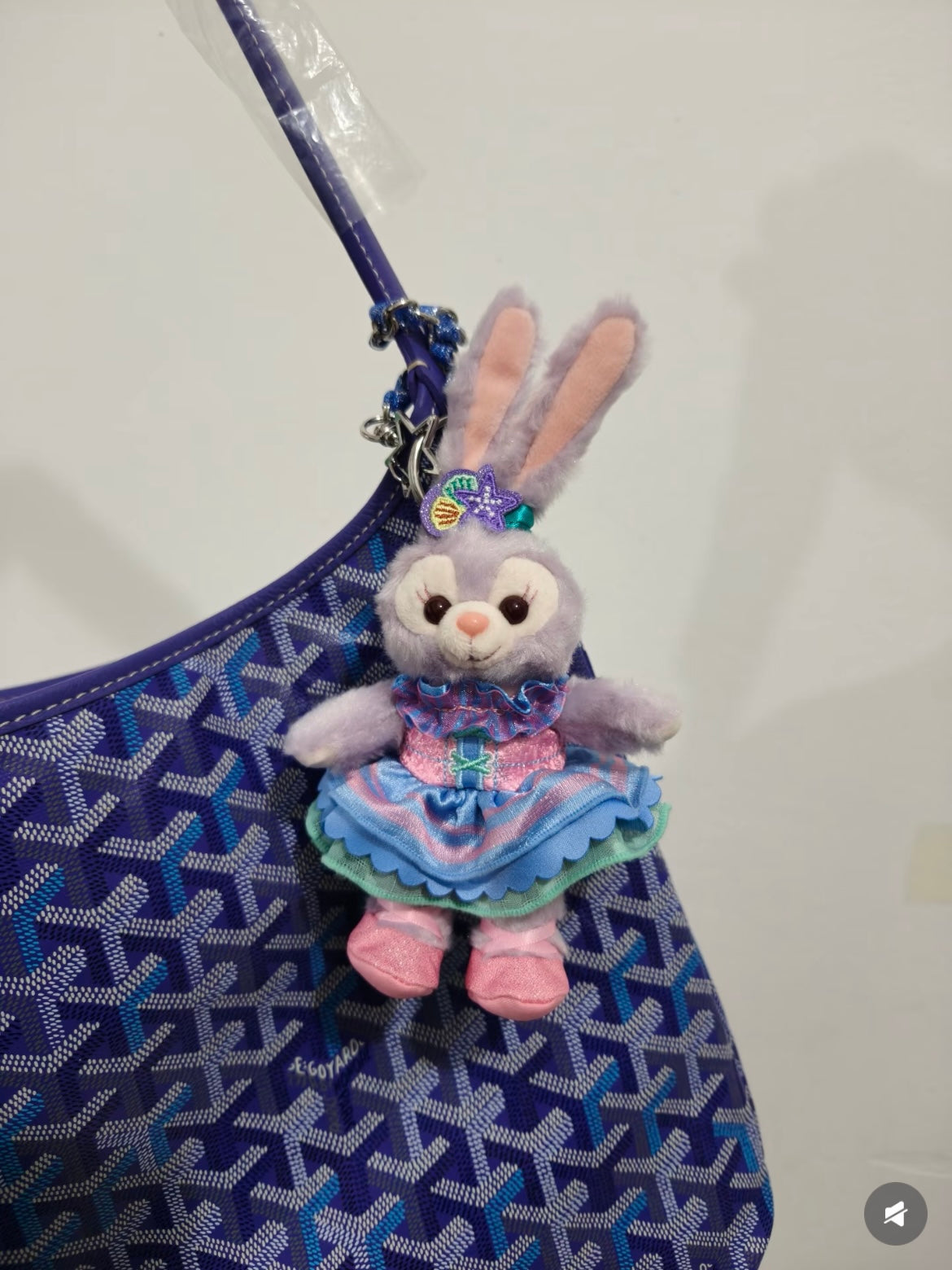 Blue patterned tote bag with long strap and plush rabbit charm hanging.