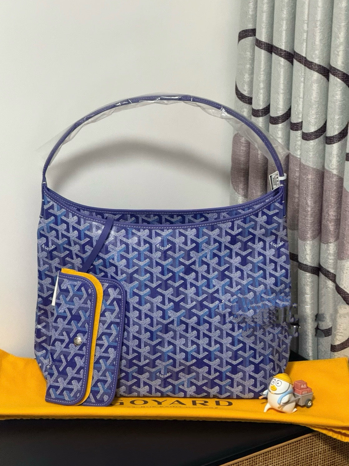 Blue patterned tote bag with top handles and small side pocket detail.