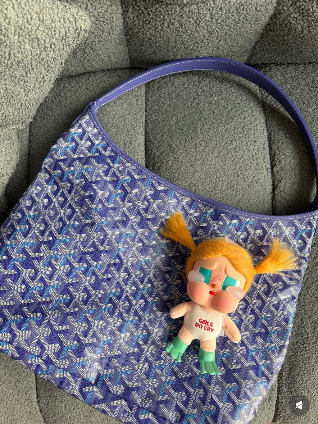 Blue patterned handbag with shoulder handles and plush charm keychain on front.